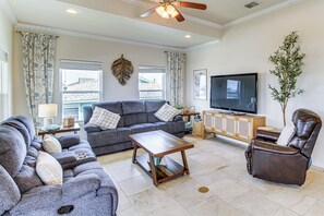 A living room with a grey sofa, a brown leather chair, a wooden coffee table, and a flat-screen TV on a wooden cabinet. - Waterfront Retreat w/ Dock in Rockport! (Rockport)