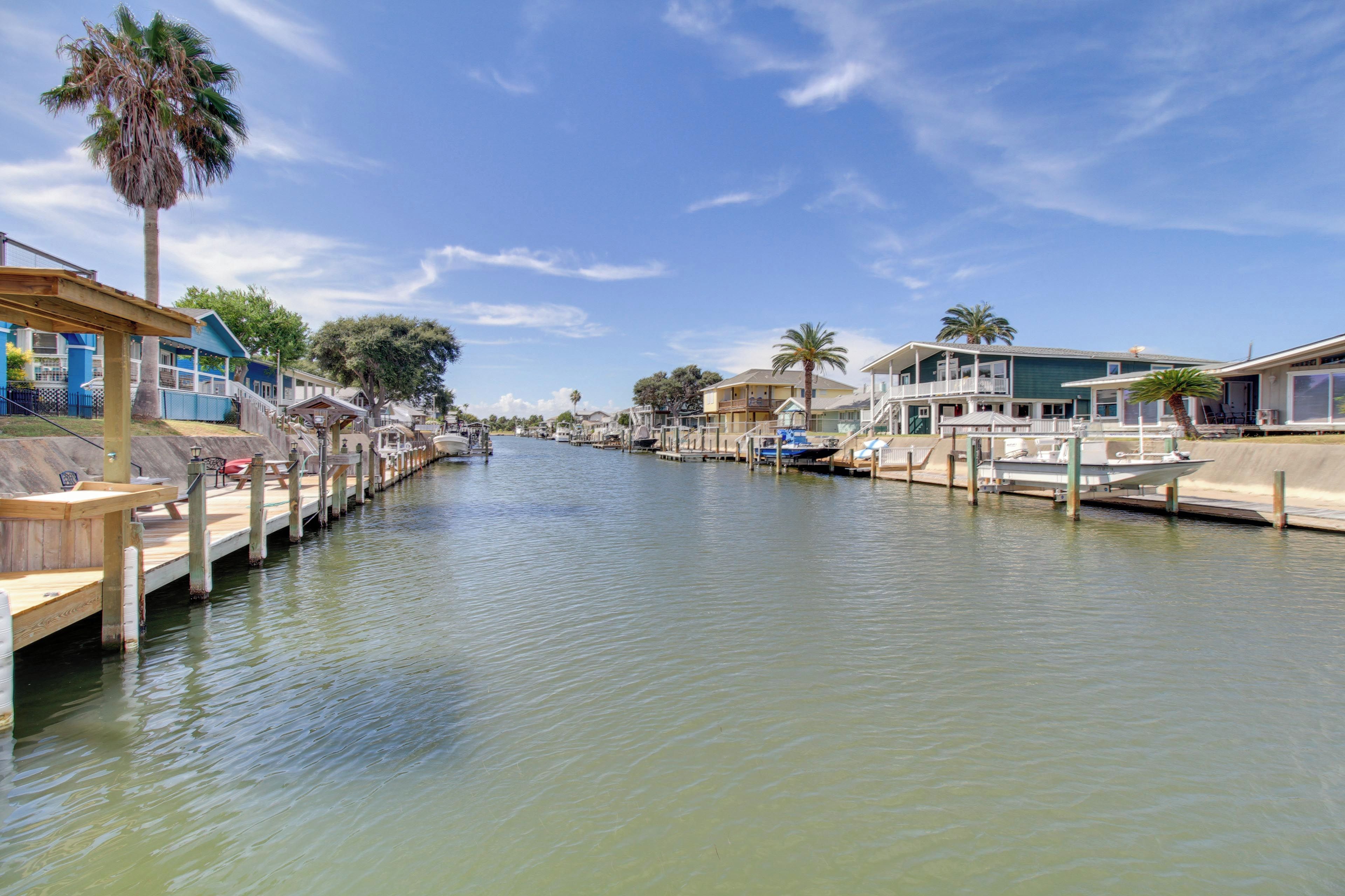 A canal with boats docked, wooden walkways, and buildings with balconies along the water's edge.