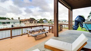 A covered deck with a wooden picnic table, lounge chairs, and a Yamaha outboard motor. - Waterfront Retreat w/ Dock in Rockport! (Rockport)