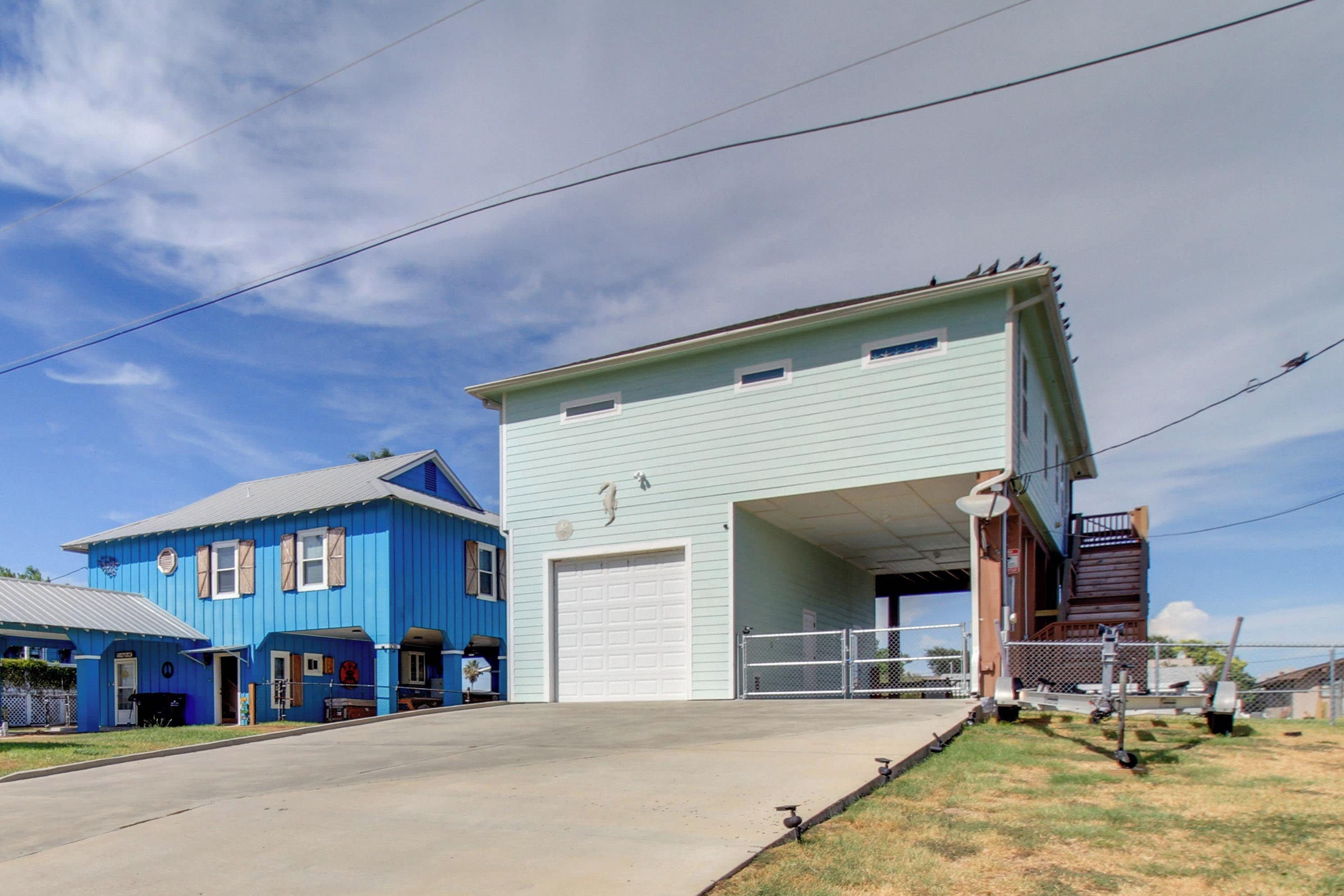 A two-story building with a garage door, a blue house to the left, and a clear sky.