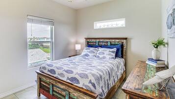 Un dormitorio con cama, mesita de noche, lámpara, ventana y vistas al exterior.