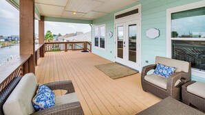 A covered deck with wicker furniture and a view of the water. - Waterfront Retreat w/ Dock in Rockport! (Rockport)