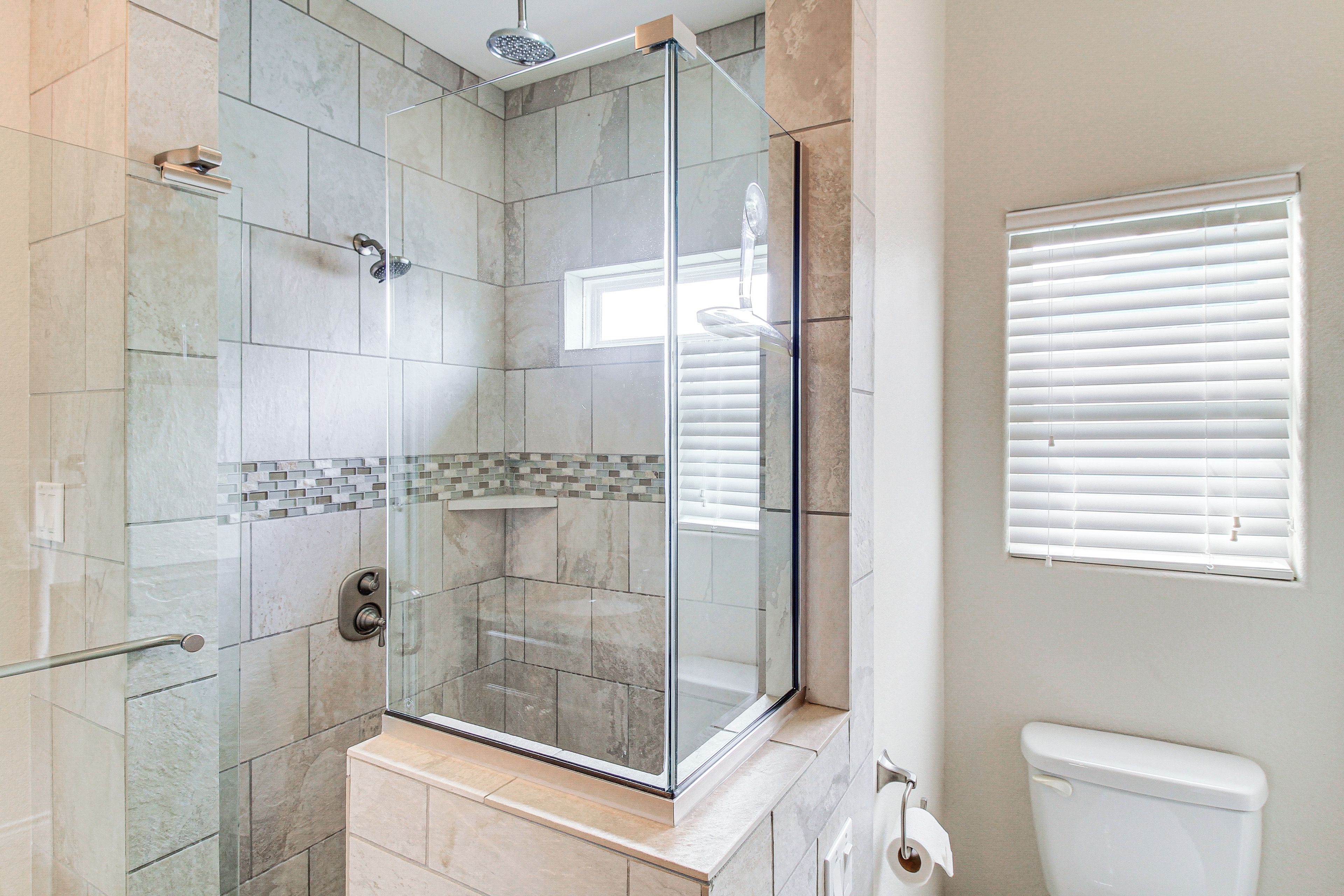 A modern bathroom with a glass-enclosed shower, tiled walls, and a toilet.