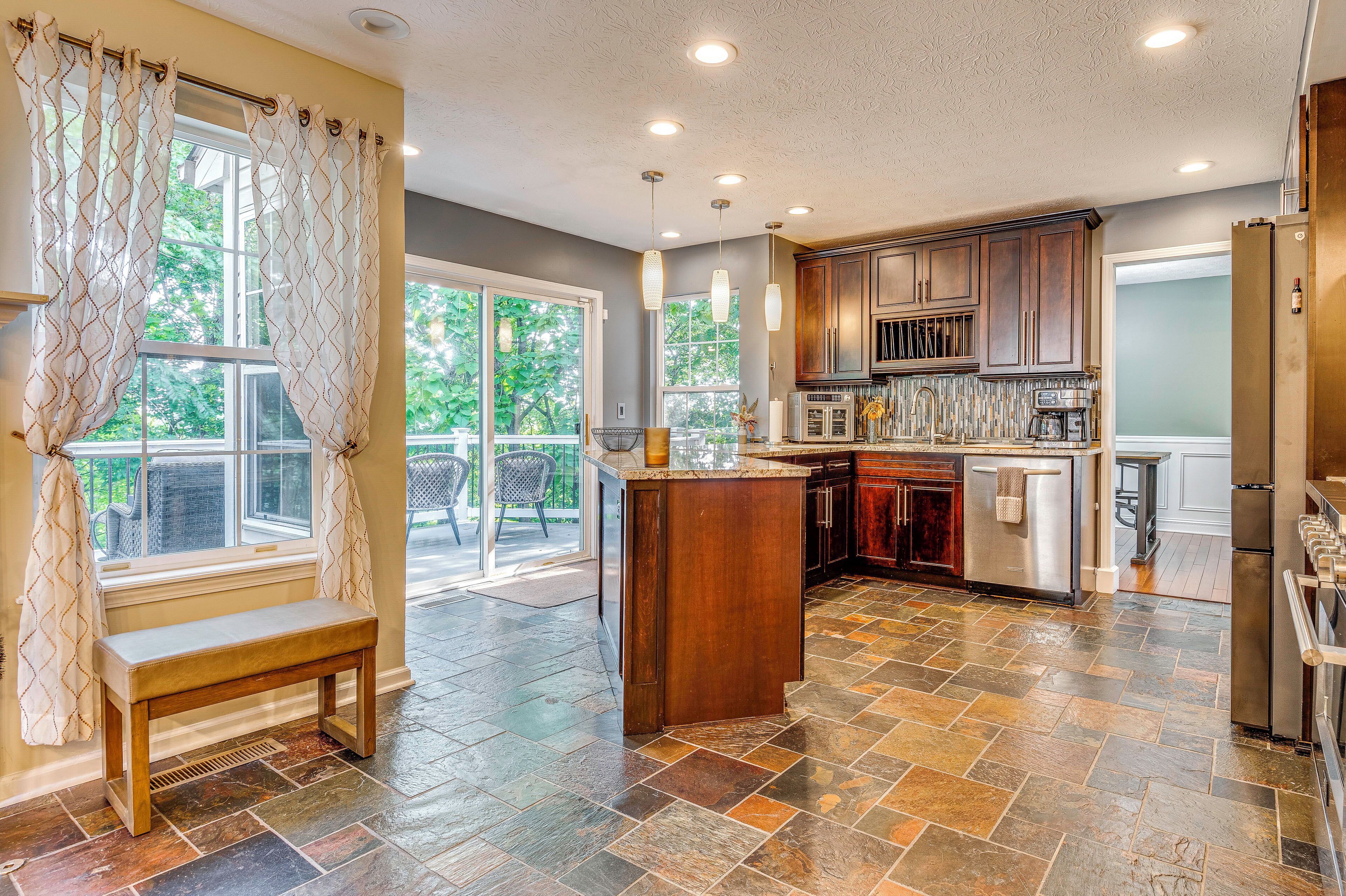 A modern kitchen with a stone tile floor, wooden cabinets, and a built-in island.
