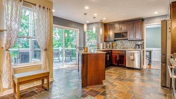 A modern kitchen with a stone tile floor, wooden cabinets, and a built-in island.