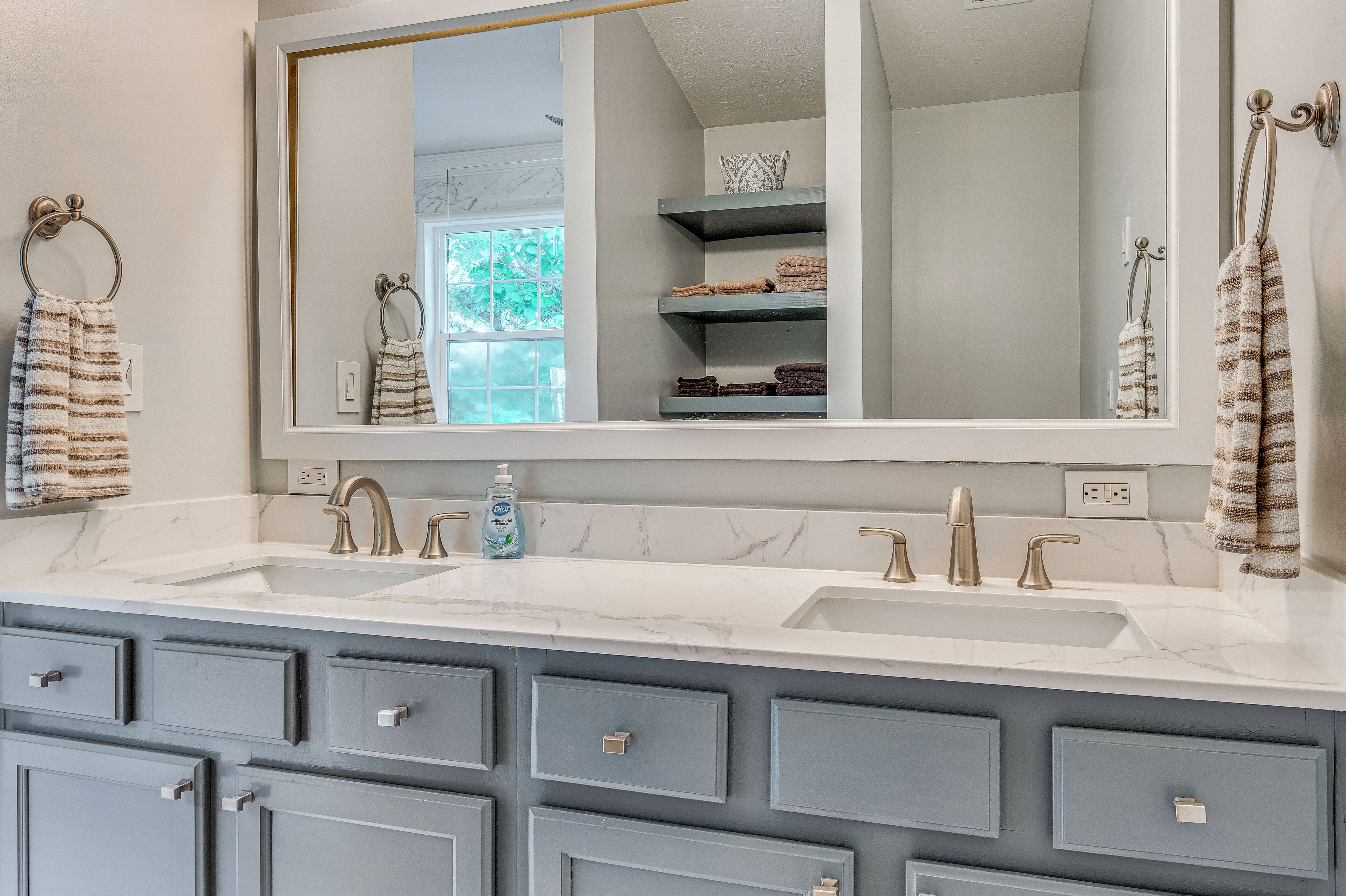 A bathroom with two sinks, a large mirror, and a towel rack.