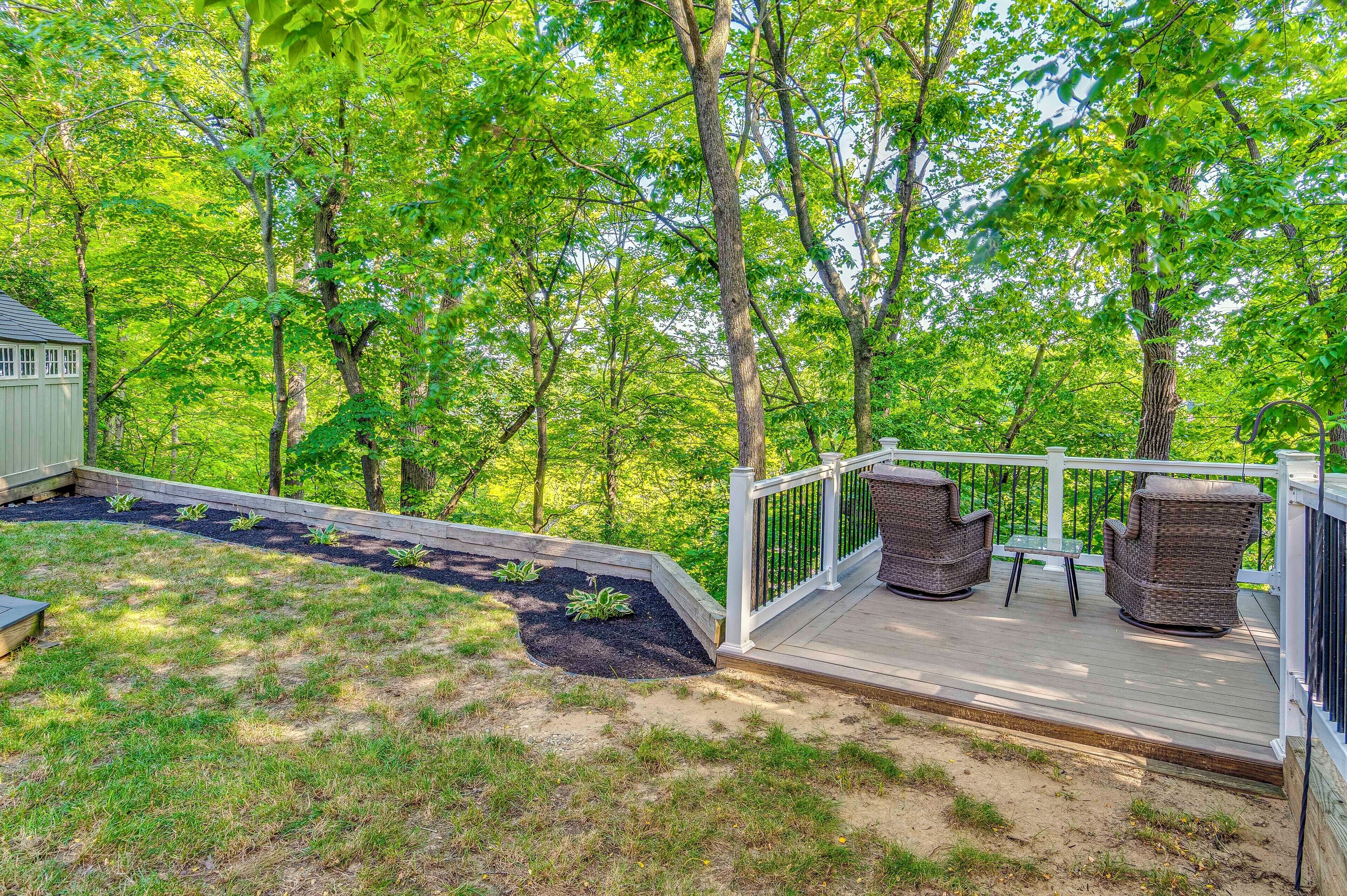 A deck with wicker furniture and a small table, surrounded by a wooden deck and a metal railing.