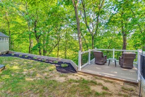 A deck with wicker furniture and a small table, surrounded by a wooden deck and a metal railing. - Treehouse Views! Walking Distance to IMS (Indianapolis)
