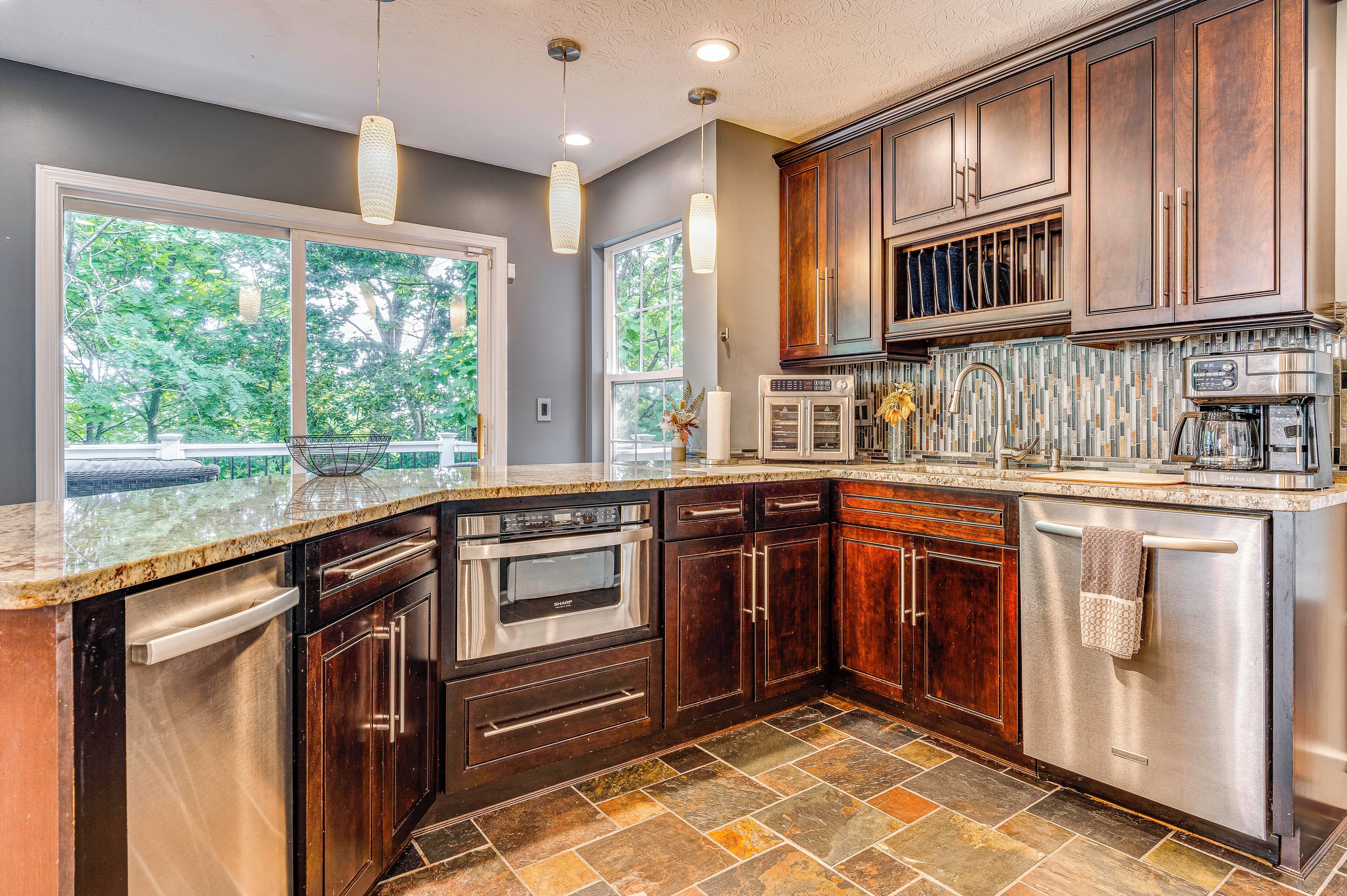 A modern kitchen with dark wood cabinets, stainless steel appliances, and a stone tile backsplash.