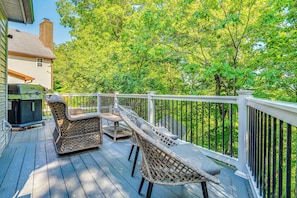 A wooden deck with wicker furniture and a grill, overlooking a lush green landscape. - Treehouse Views! Walking Distance to IMS (Indianapolis)