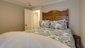 A bedroom with a wooden headboard, a bed with patterned bedding, a bedside table, and a door leading to another room. - 'the Hand House!' Walk to Downtown & Race Course (Saratoga Springs)