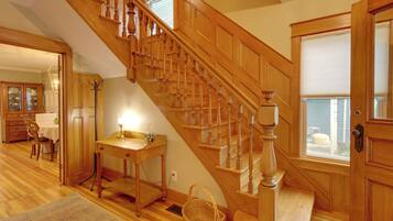 A wooden staircase with a handrail, a dining area with a table and chairs, and a door with a window.
