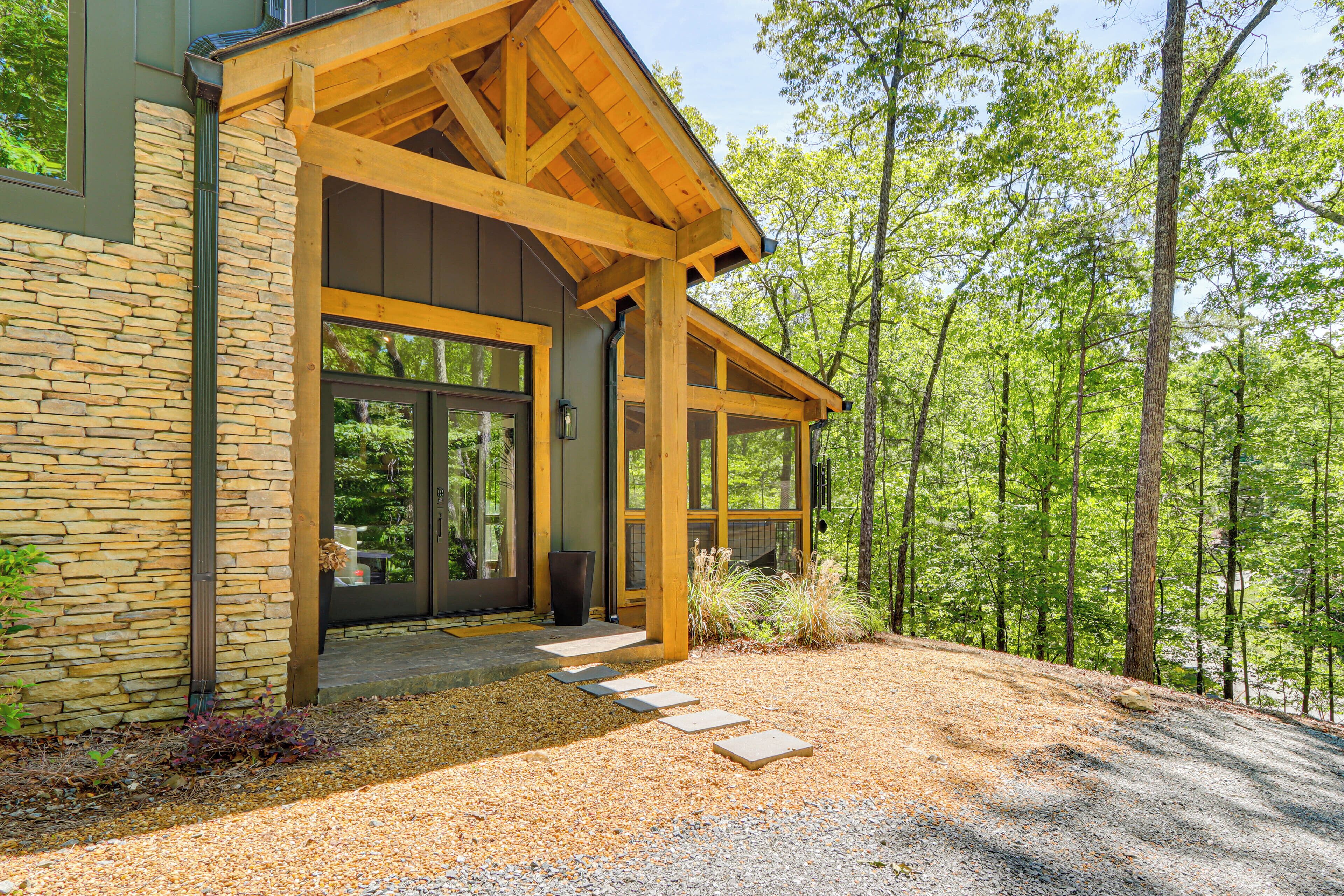 Une maison moderne avec une façade en pierre, de grandes fenêtres et une terrasse en bois.