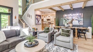 A spacious living area with a high ceiling, a staircase, and a dining area. - Screened Porch + Home Office: Modern Ellijay Cabin (Ellijay)