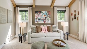 A living room with a sofa, two side tables, a coffee table, and a painting on the wall. - Screened Porch + Home Office: Modern Ellijay Cabin (Ellijay)