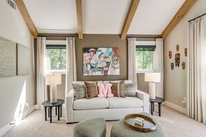 Ein Wohnzimmer mit einer Couch, zwei Beistelltischen, einem Couchtisch und einem Gemälde an der Wand.
