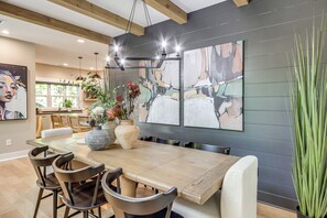 A dining area with a wooden table, chairs, and artwork on the wall. - Screened Porch + Home Office: Modern Ellijay Cabin (Ellijay)