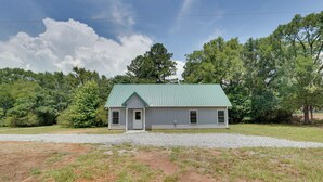 A single-story house with a green metal roof, a front porch, and a gravel driveway. - < 1 Mi to Broad River Campground! Rural Retreat (Tignall)