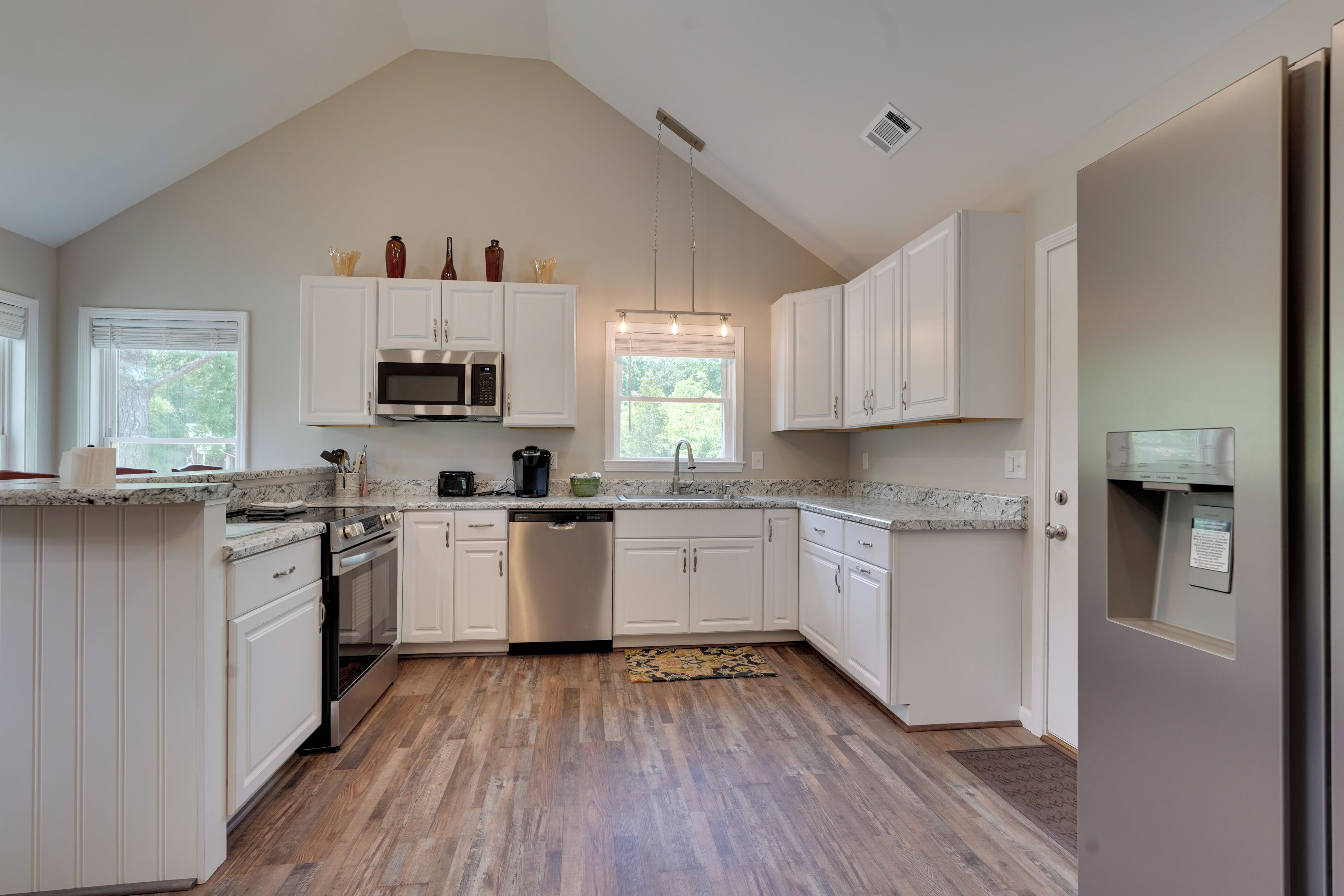 A modern kitchen with white cabinetry, a stainless steel dishwasher, and a granite countertop.
