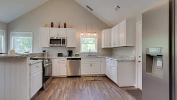 A modern kitchen with white cabinetry, a stainless steel dishwasher, and a granite countertop.