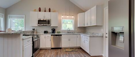 A modern kitchen with white cabinetry, a stainless steel dishwasher, and a granite countertop.