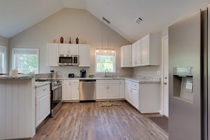 A modern kitchen with white cabinetry, a stainless steel dishwasher, and a granite countertop.