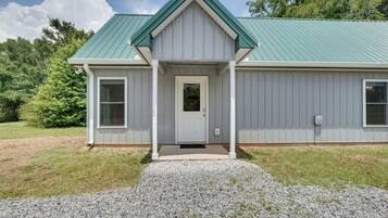 A single-story building with a green roof, a front door, and a gravel driveway.