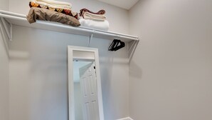 A walk-in closet with a white door, a hanging rod with folded clothes, and a wooden floor. - < 1 Mi to Broad River Campground! Rural Retreat (Tignall)