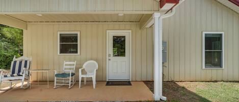 A building with a covered porch, a door, and two windows.
