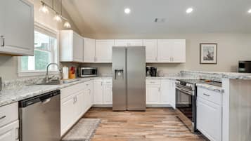 A kitchen with white cabinets, stainless steel appliances, a dishwasher, and a granite countertop.