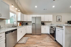 A kitchen with white cabinets, stainless steel appliances, a dishwasher, and a granite countertop.