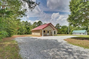A single-story building with a red roof, a gravel driveway, and a green lawn.