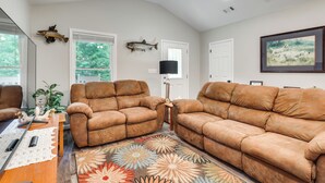 A living room with two brown leather sofas, a wooden coffee table, a patterned rug, and a fish mounted on the wall. - Hunt & Fish! Home < 1 Mi to Broad River Campground (Tignall)
