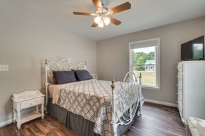 A bedroom with a bed, a nightstand, a dresser, a ceiling fan, and a window.