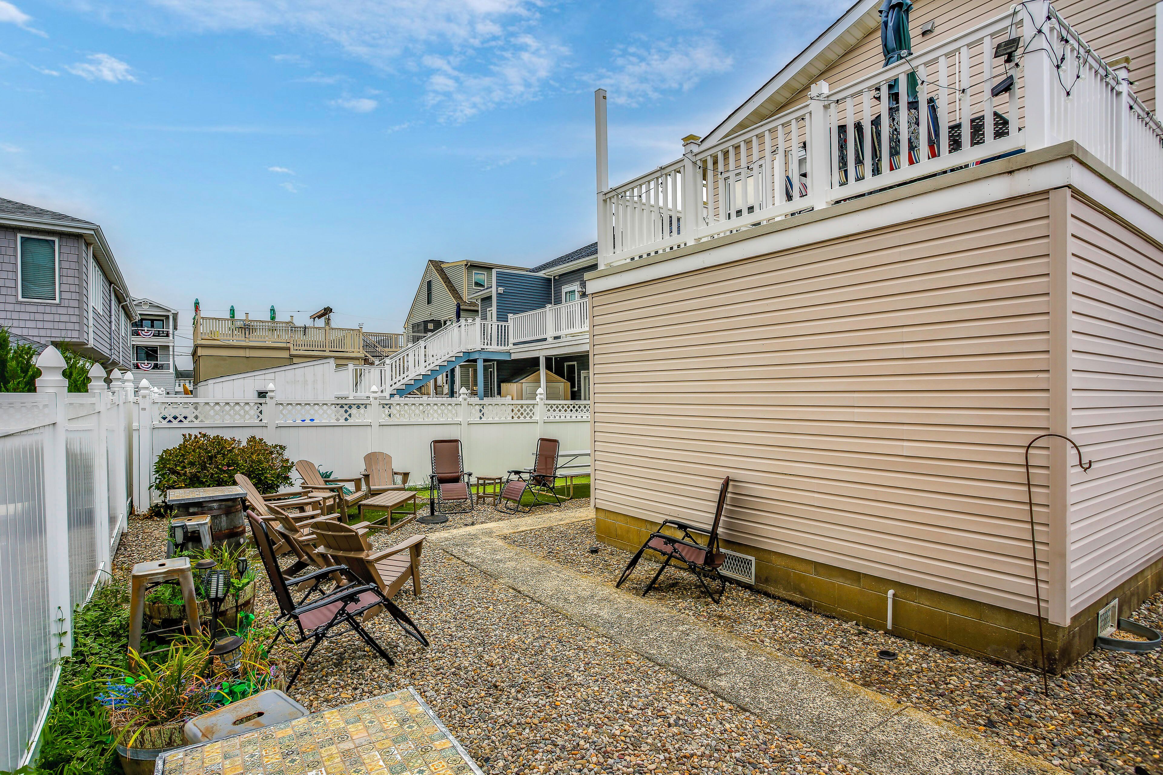 A residential area with a patio, outdoor seating, and a white fence.