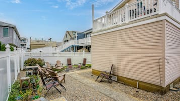 A residential area with a patio, outdoor seating, and a white fence.