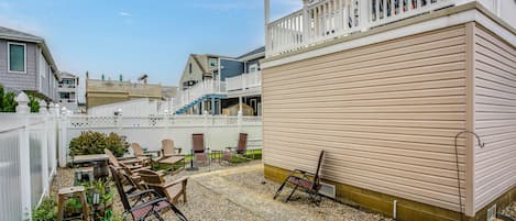 A residential area with a patio, outdoor seating, and a white fence.