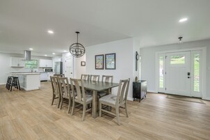 A modern kitchen with white cabinets, a central island, and a dining area with a wooden table and chairs.