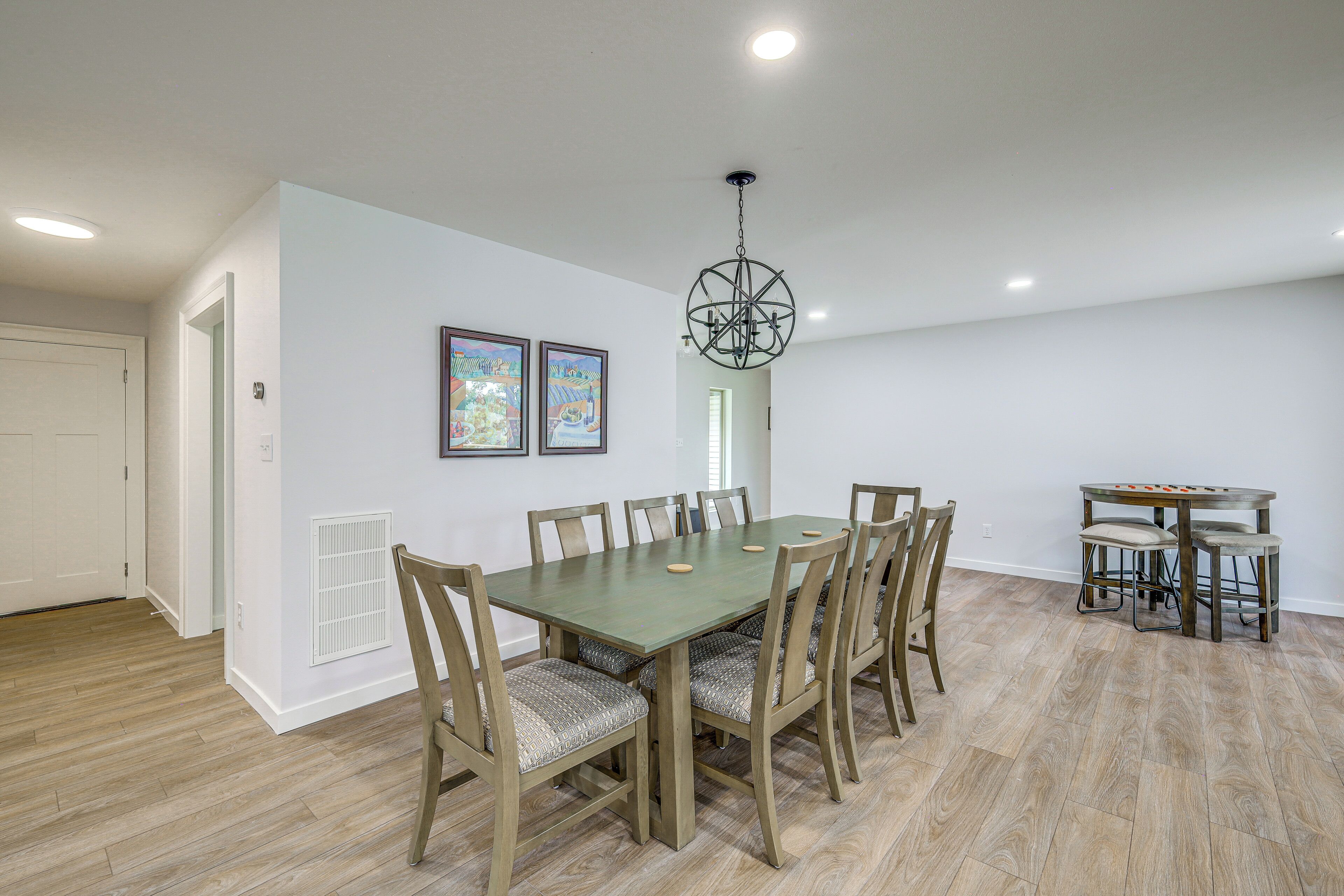 A dining area with a table and chairs, a chandelier, and framed artwork on the wall.