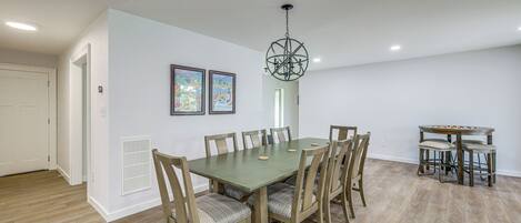 A dining area with a table and chairs, a chandelier, and framed artwork on the wall.
