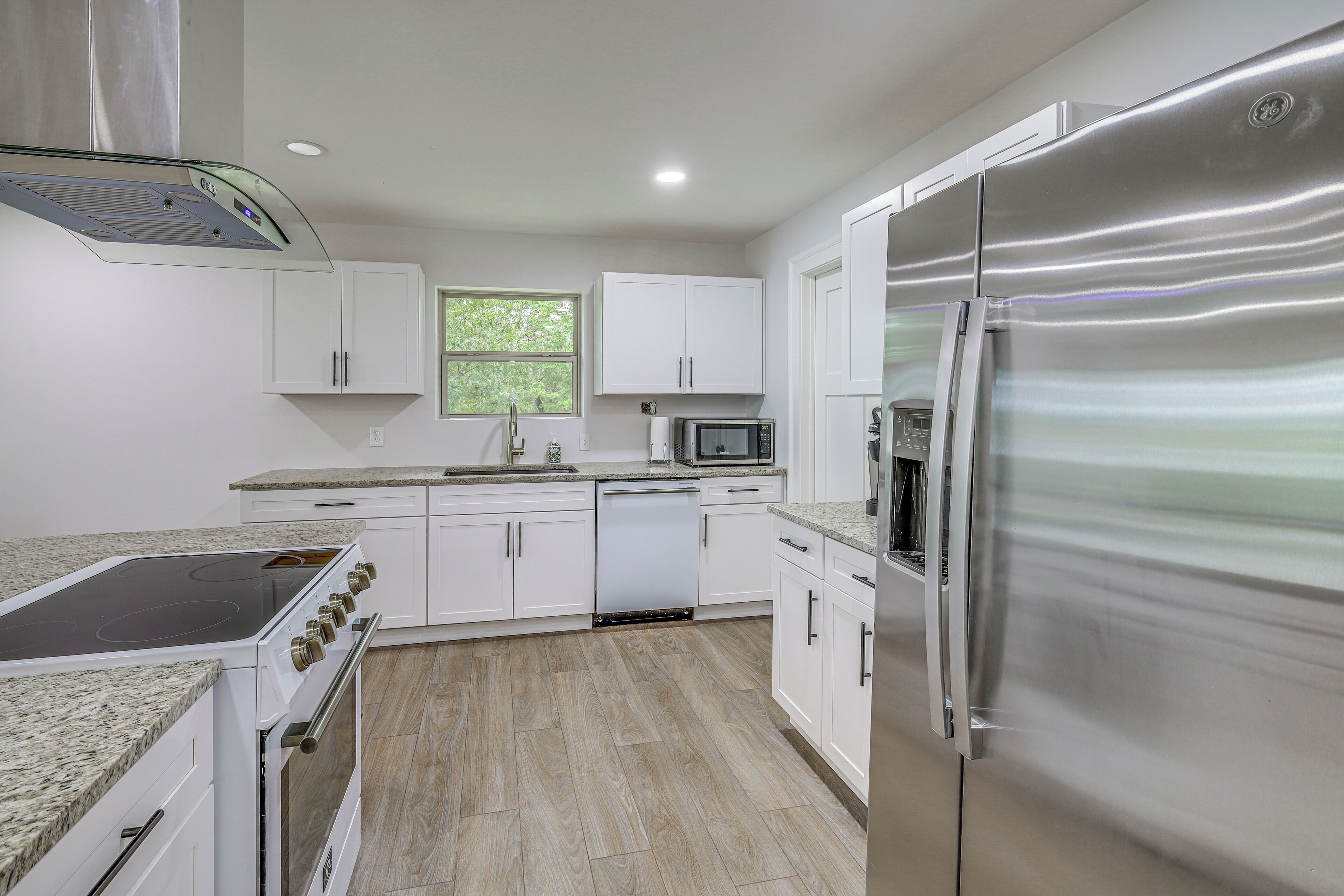 Una cocina moderna con armarios blancos, un refrigerador de acero inoxidable, un microondas y un lavavajillas.