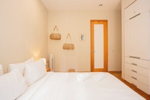 A hotel room with a bed, a wardrobe, a door, and two wall-mounted baskets. - Escandon Apt: Private Patio & Steps to Condesa (Mexico City)
