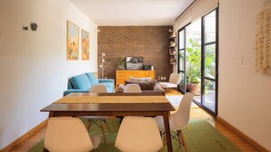 A dining area with a table, chairs, a sofa, and a brick wall. - Escandon Apt: Private Patio & Steps to Condesa (Mexico City)