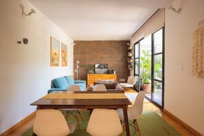 A dining area with a table, chairs, a sofa, and a brick wall. - Escandon Apt: Private Patio & Steps to Condesa (Mexico City)