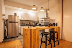 Een moderne keuken met een houten keukeneiland, roestvrijstalen apparatuur en hangende吊灯.