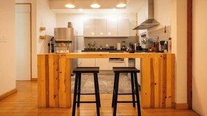 A modern kitchen with a central island, bar stools, and pendant lighting. - Escandon Apt: Private Patio & Steps to Condesa (Mexico City)