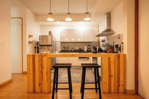 A modern kitchen with a central island, bar stools, and pendant lighting. - Escandon Apt: Private Patio & Steps to Condesa (Mexico City)
