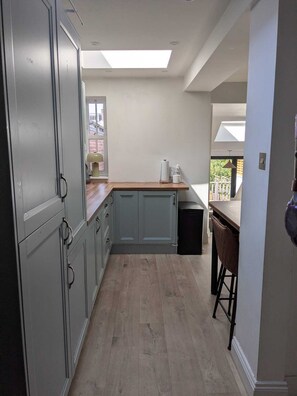 A kitchen with grey cabinets, a wooden countertop, and a black trash bin. - Period Home in the Heart of Winchester (Winchester)