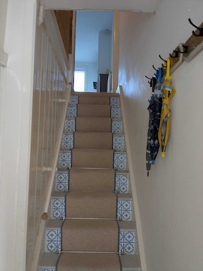 A carpeted staircase with patterned tiles at the bottom, leading to a room with a door and a window. - Period Home in the Heart of Winchester (Winchester)