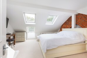 Un dormitorio con una cama, un escritorio y dos tragaluces.